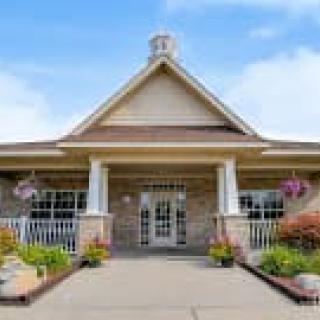 A welcoming building entrance with a front porch and floral decorations.