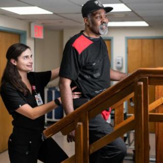 A healthcare professional assists a man during a physical therapy session.