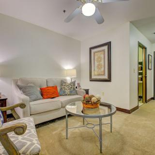 A cozy living room with a beige sofa, colorful cushions, and a glass coffee table, complemented by wall art and ambient lighting.