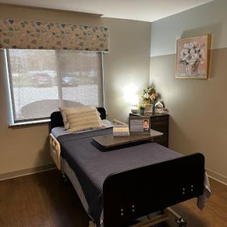 A serene hospital room featuring a patient bed, a small bedside table, and natural light filtering through the window.