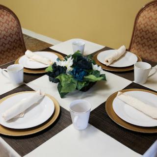 A beautifully set dining table with plates, cups, and a floral centerpiece.