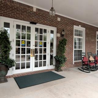 Front entrance with glass doors, potted plants, and seating area.