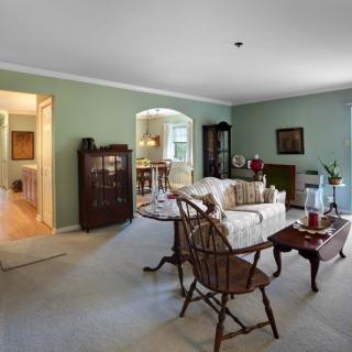 A traditional living room with green walls, featuring a sofa, armchairs, and wooden furniture.