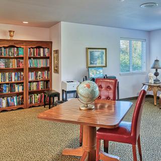 A cozy library room with bookshelves, a table with a globe, and two leather chairs.
