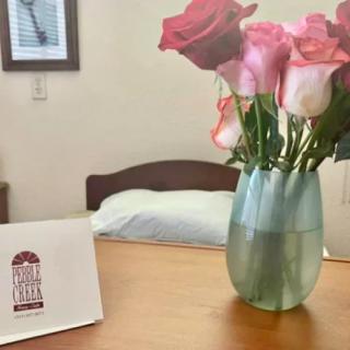A vase of roses on a table next to a greeting card in a bedroom setting.