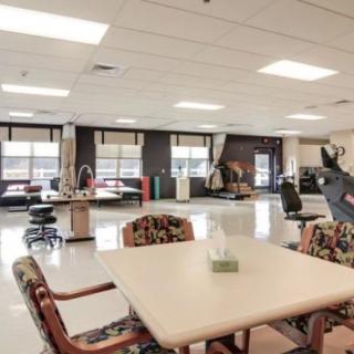 A spacious rehabilitation center with exercise equipment and seating areas.