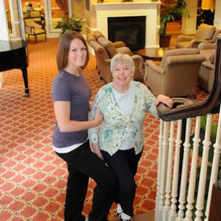 A young woman and an elderly lady posing together in a cozy indoor setting.