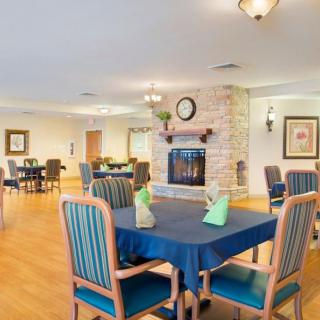 A cozy dining area with neatly arranged tables and a central fireplace.