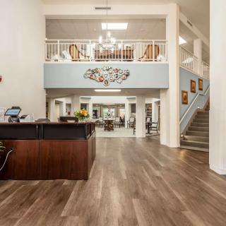 A spacious modern lobby with a wooden floor, featuring a reception desk and staircase.