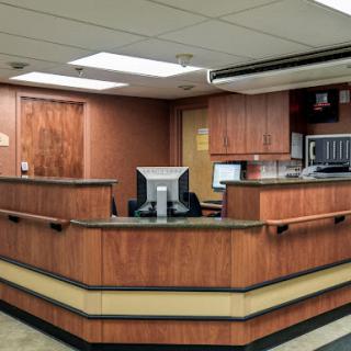 A modern reception area in a healthcare setting, featuring wooden cabinetry and a computer workstation.