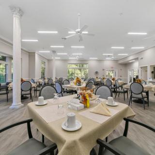 A spacious and elegantly arranged dining area with multiple tables set for guests.