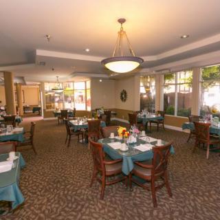 An elegant dining room with neatly arranged tables and chairs, featuring warm lighting and tasteful decor.