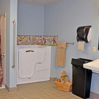 A well-equipped, accessible bathroom featuring a walk-in bathtub, grab bars, sink, and towel holder.