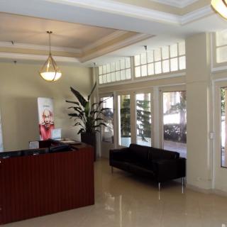 A well-lit lobby with a reception desk, sofa, and decorative plants.
