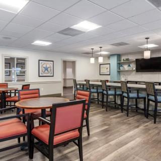 A modern dining area featuring tables and chairs with a bar counter in the background.