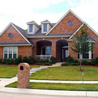 A suburban brick house with a well-maintained front yard and mailbox.
