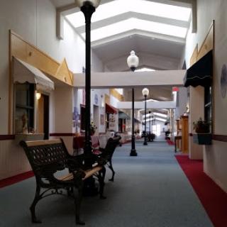 A quiet indoor shopping mall corridor featuring benches and decorative lampposts.