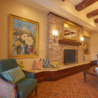 A cozy living room featuring a stone fireplace, elegant artwork, and comfortable seating.