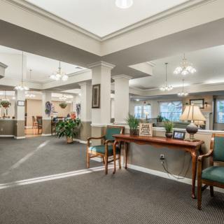 A spacious lobby with traditional furnishings and warm lighting, featuring seating arrangements and decorative elements.