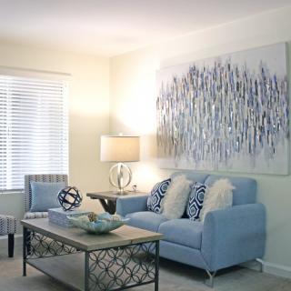 A modern living room with a light blue sofa, abstract artwork, and a stylish coffee table.