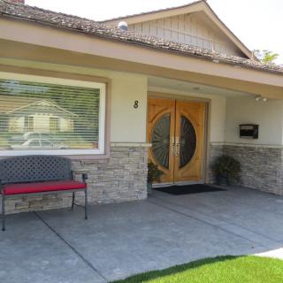 Front entrance of a house with a wooden door and a bench on the porch.