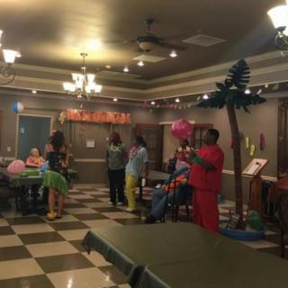 A group of people gathered in a room decorated for a celebration with balloons and party decorations.