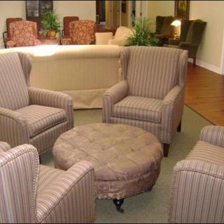 A cozy seating arrangement with striped armchairs and a round ottoman in a living room setting.