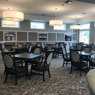 A spacious dining room with multiple tables, chairs, and elegant lighting fixtures.