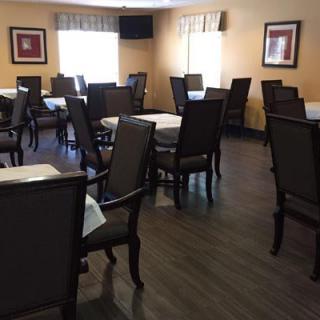 An empty dining room with neatly arranged tables and chairs, illuminated by natural light through the windows.