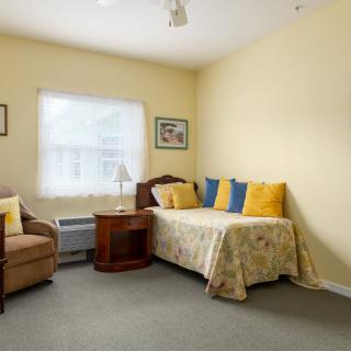 A cozy bedroom with a bed, sofa, and window creating a warm atmosphere.