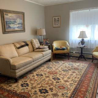 A cozy living room with a sofa, armchairs, and a patterned rug.