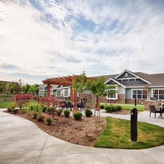 A scenic view of a well-maintained garden with a house, featuring a pathway and seating area.
