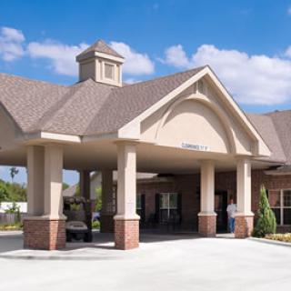 A modern building entrance with columns and a peaked roof against a blue sky.