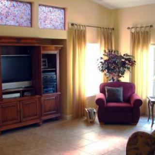 A cozy living room with an armchair, entertainment center, and decorative touches.