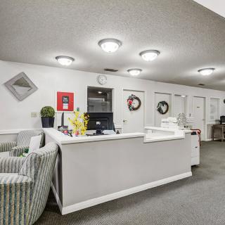 A well-lit reception area with a central desk and comfortable seating.