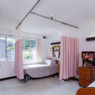 A clean hospital room with a bed and pink privacy curtains.