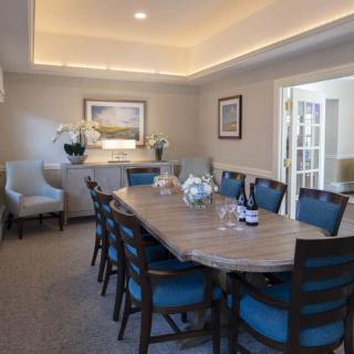 A modern dining room with a large table and upholstered chairs, adorned with artwork and decorative elements.