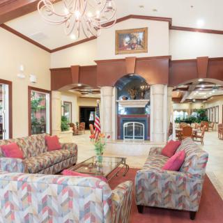 A spacious and elegantly designed living room with patterned sofas, a central fireplace, and a decorative chandelier.