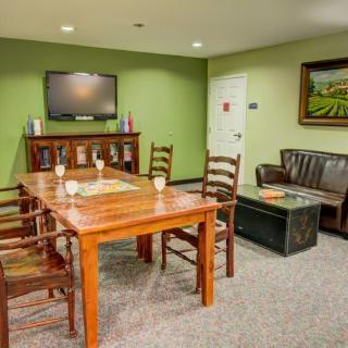 A cozy conference room with a wooden table, chairs, and a television on a green wall.