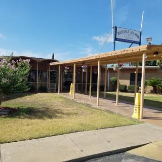 A view of a building with a wooden overhang and landscaped surroundings.
