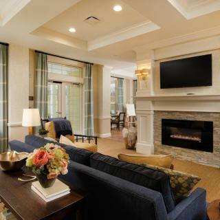 A cozy and elegant living room with a fireplace, modern furnishings, and a large television mounted above the mantel.