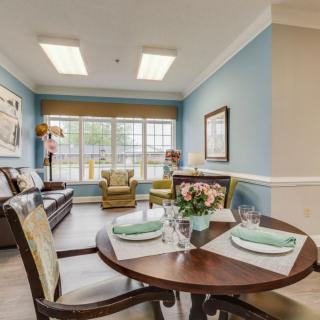 A cozy living and dining area with blue walls, modern furniture, and a large window.