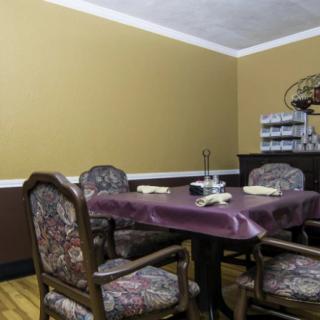 A traditional dining room with a table and chairs, featuring warm-toned walls and decorative elements.