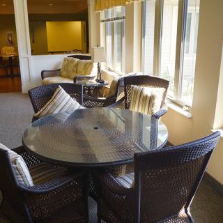A cozy indoor dining area with a round table and wicker chairs, bathed in natural light from nearby windows.