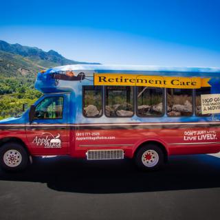 A colorful 'Retirement Cart' bus parked against a scenic mountain backdrop.