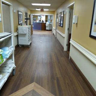 A well-lit hallway in a medical facility, featuring a cart and decorative artwork.