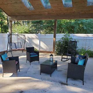A cozy outdoor patio with wicker furniture under a wooden pergola, perfect for relaxation.
