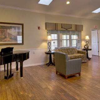A cozy living room with a grand piano and comfortable seating.