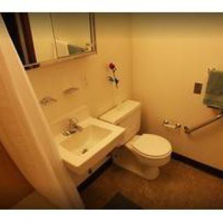 A small bathroom featuring a sink, toilet, and mirror.