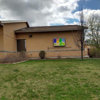 A view of a building's exterior with a colorful sign against a backdrop of clouds.